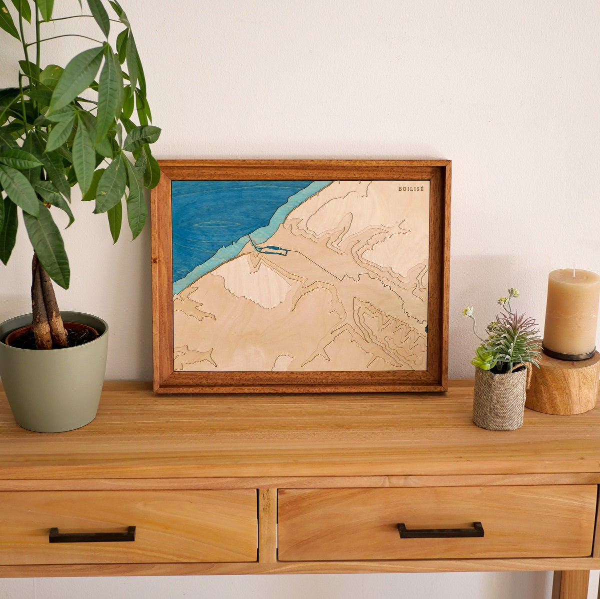 Décoration d'une commode d'entrée en bois avec une plante et une carte topographique